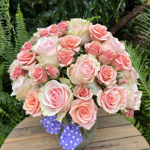 Bouquet of pink roses in a vase with a purple polka-dot ribbon