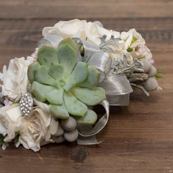 White floral wrist corsage with a green succulent and silver ribbon