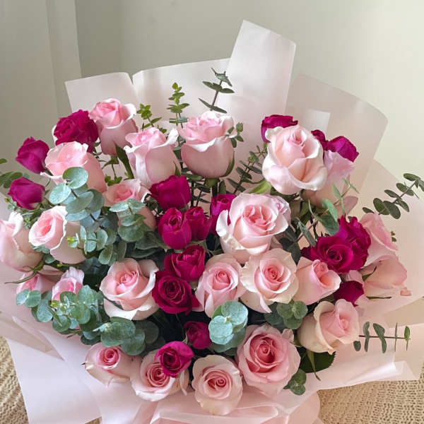Bouquet of pink and magenta roses wrapped in pale pink paper