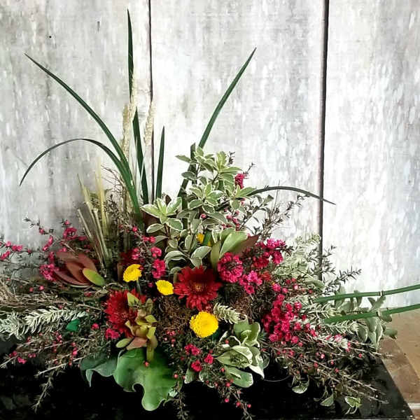 Large mixed floral arrangement with red and yellow blooms and tall greenery
