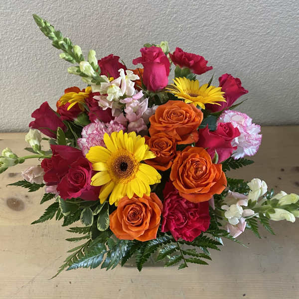 Mixed bouquet of orange and pink roses with yellow daisies in a vase