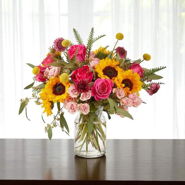 Bouquet of sunflowers and pink roses in a clear glass vase