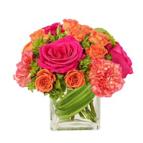 Pink and orange roses in a clear square vase