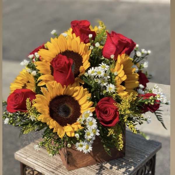 Bouquet of red roses and sunflowers in a wooden box