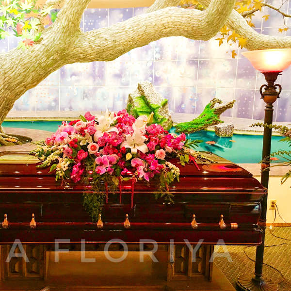 Pink and white floral spray on a dark casket
