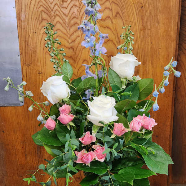 Pink and white roses with blue delphinium in a glass vase