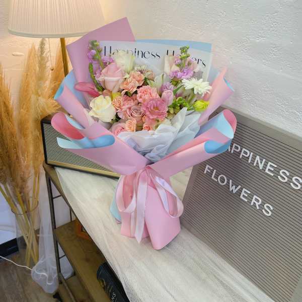 Pastel bouquet of pink, white, and lavender flowers wrapped in pink and blue paper