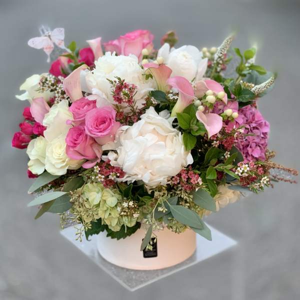 Pink and white mixed flower arrangement in a round box