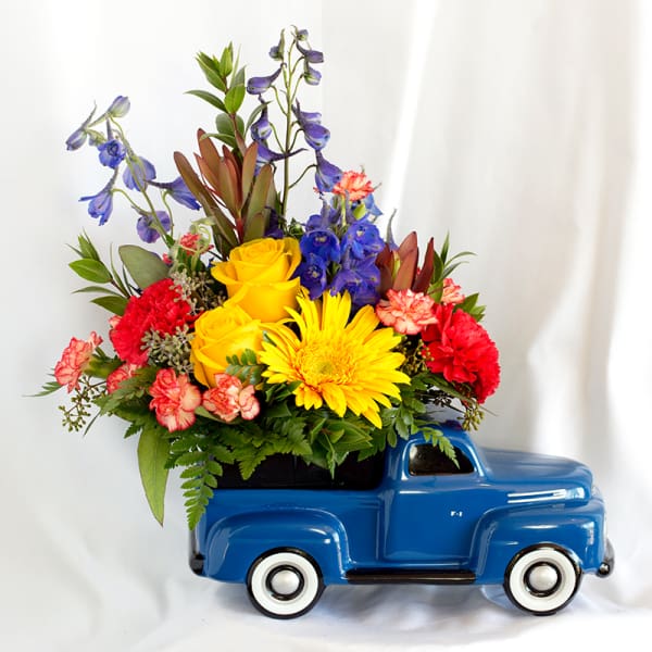 Colorful flower arrangement in a blue ceramic truck planter