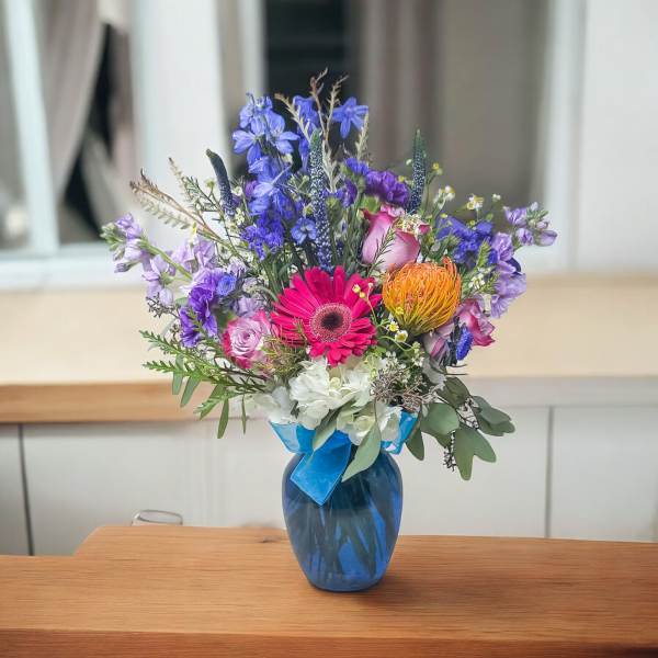 Mixed bouquet in a blue vase with pink, purple, orange, and white flowers