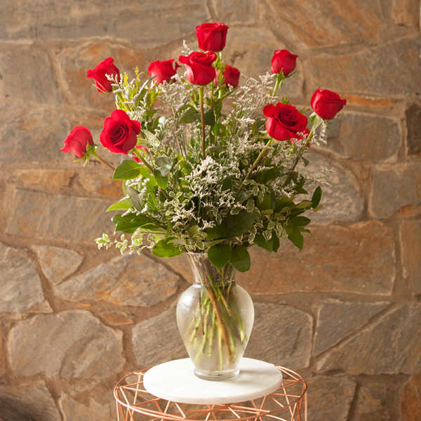 Red roses in a clear glass vase with white filler flowers