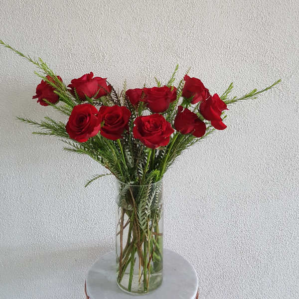 Red roses in a clear glass vase with airy greenery