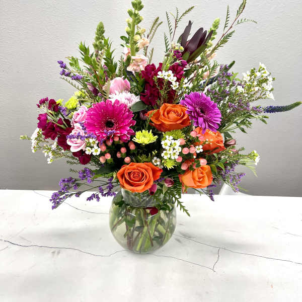 Mixed bouquet of orange and pink flowers in a glass vase