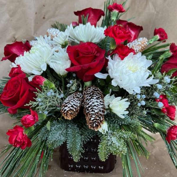 Red roses and white chrysanthemums in a dark vase with pinecones