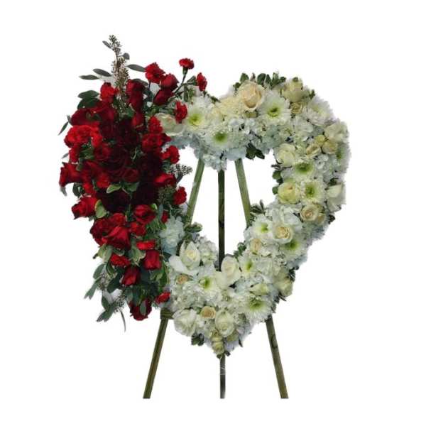 Heart-shaped funeral wreath with red and white flowers on a stand