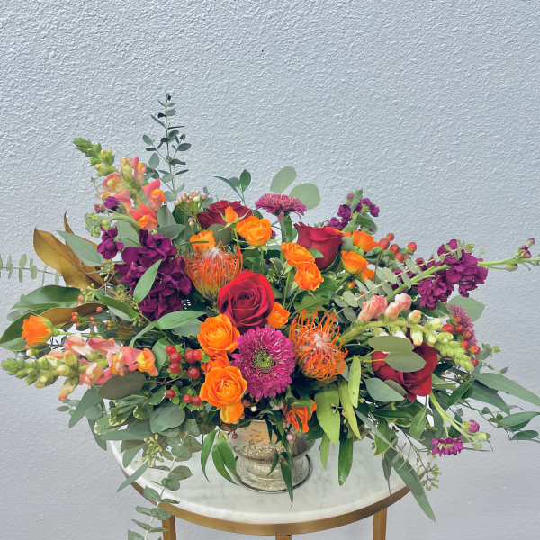 Mixed bouquet of roses, snapdragons, and protea in a silver vase