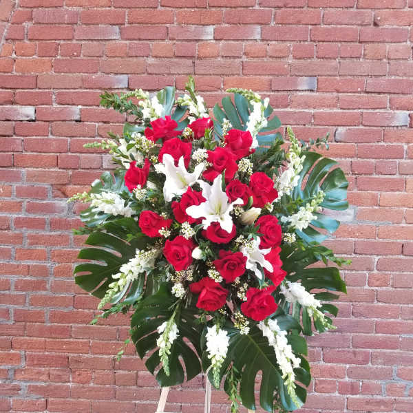 Standing floral spray of red roses and white lilies on an easel
