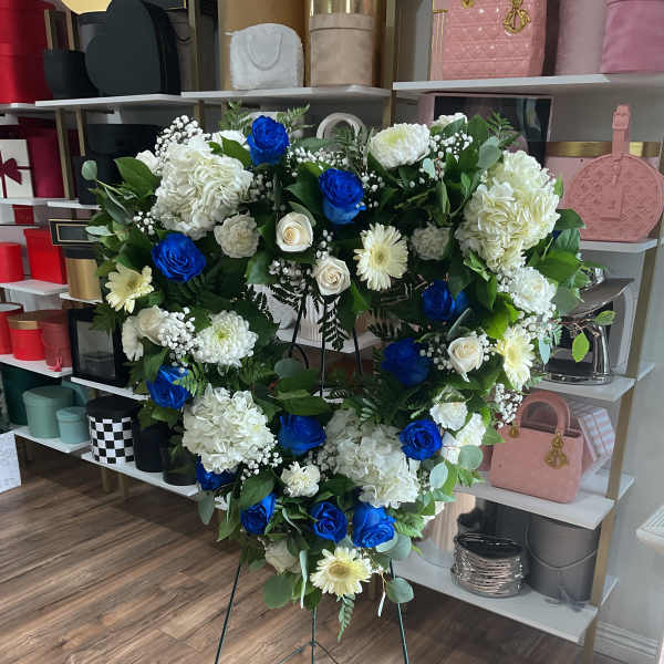 Heart-shaped floral wreath on a stand with blue and white flowers