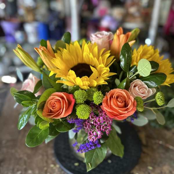 Bouquet of sunflowers, roses, and lilies in a black vase
