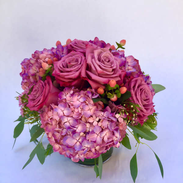 Pink roses and hydrangeas arranged in a low glass vase