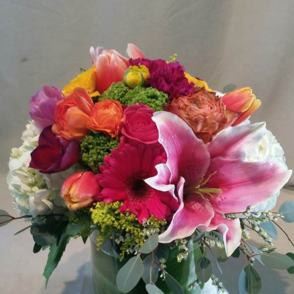 Colorful mixed bouquet in a glass vase with a large pink lily