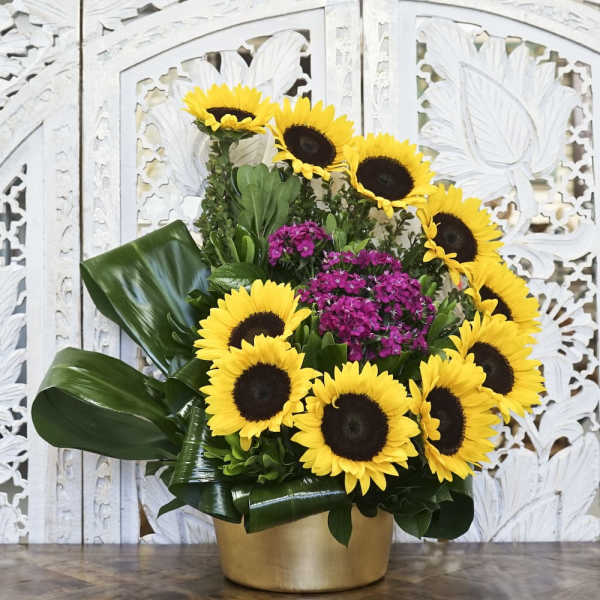 Sunflower arrangement with magenta flowers in a gold container