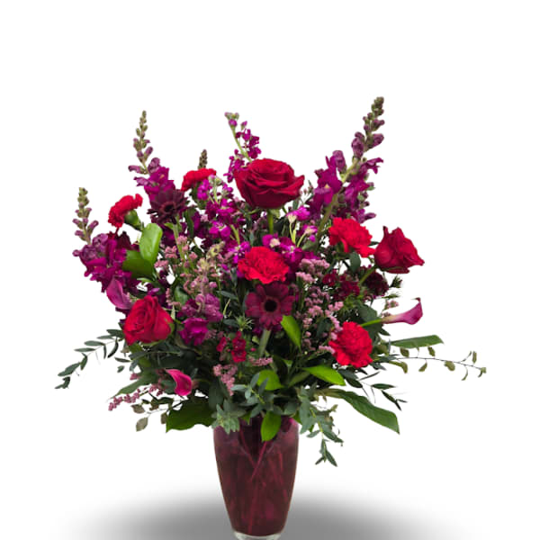 Red and magenta flowers arranged in a tall vase