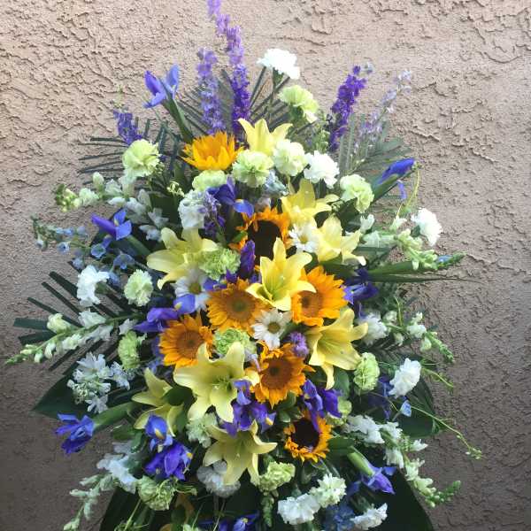 Standing floral spray with sunflowers, lilies, and purple blooms
