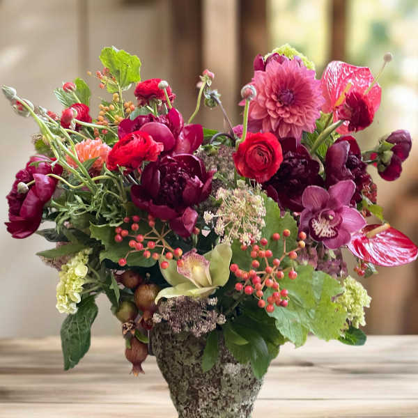 Mixed pink and burgundy flowers arranged in a stone vase