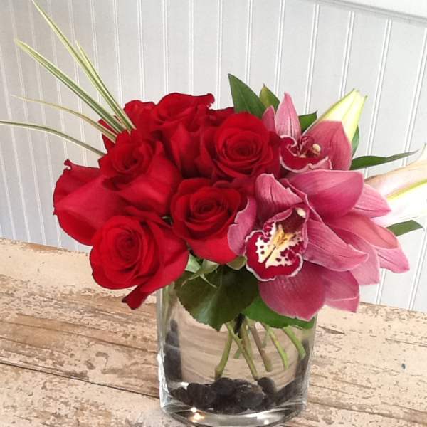 Red roses and pink orchids in a clear glass vase