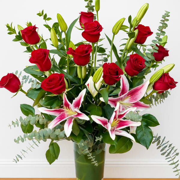 Red roses and pink lilies in a clear glass vase