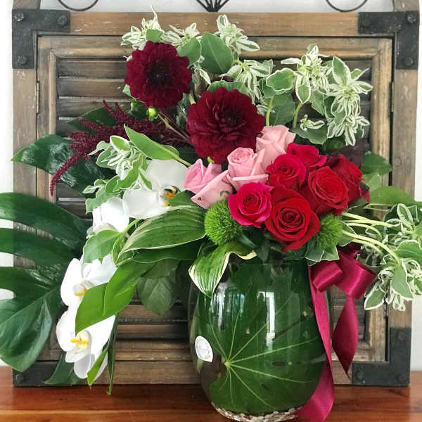 Bouquet of red and pink roses with white orchids in a glass vase