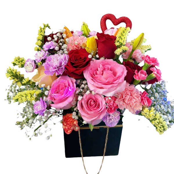 Mixed bouquet of roses, carnations, and lilies in a black gift bag with a red heart topper