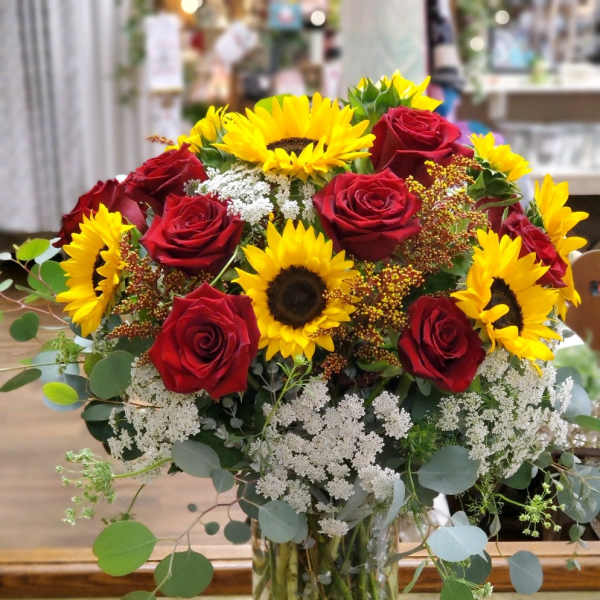 Bouquet of red roses and yellow sunflowers in a clear glass vase