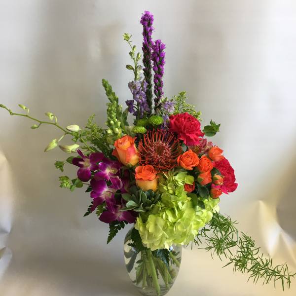 Colorful mixed bouquet in a clear glass vase with tall purple spikes