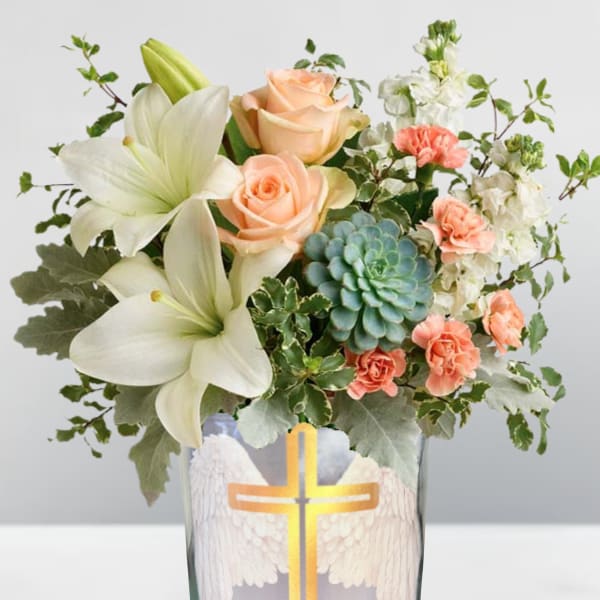 Peach roses and white lilies in a glass vase with a cross design