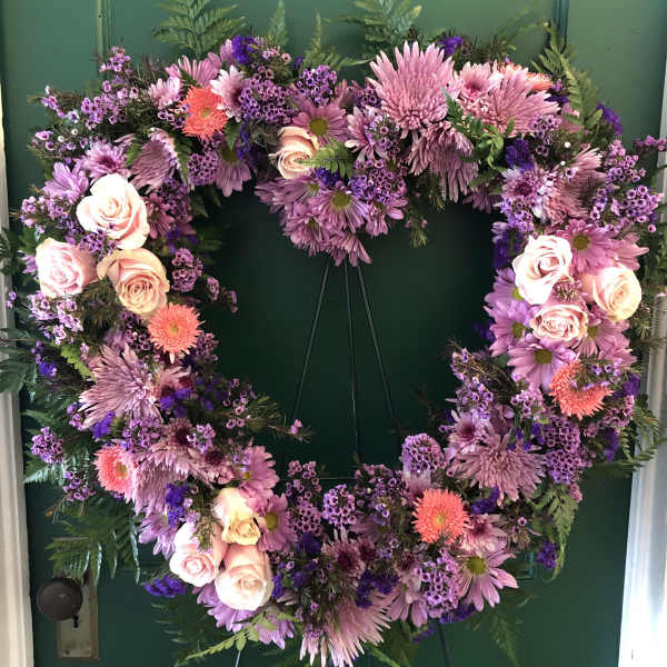 Heart-shaped floral wreath with pink and purple flowers on a green door