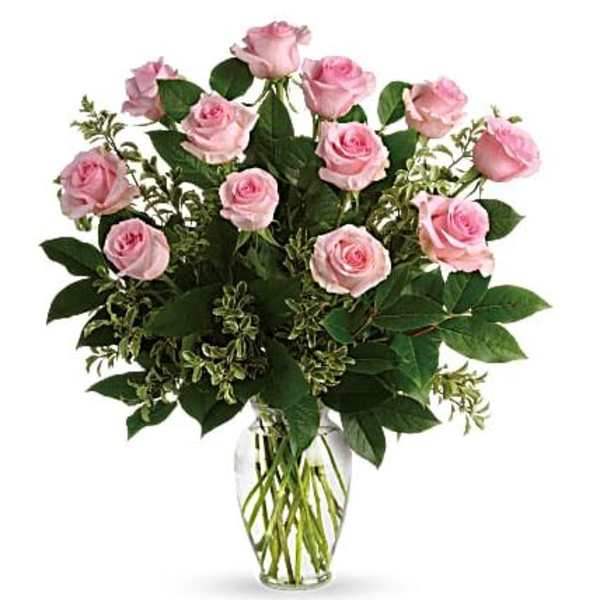 Arrangement of light pink roses with lush foliage in a clear glass vase