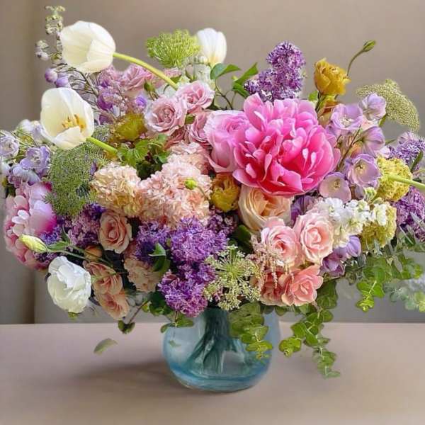 Mixed pink, purple, and white flowers in a blue glass vase