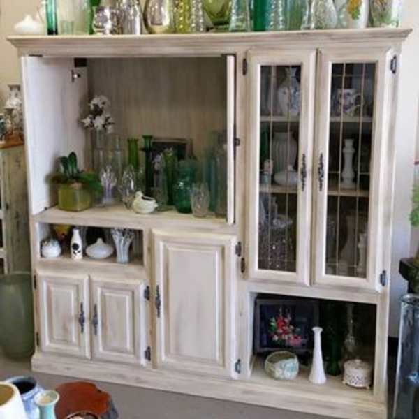 White cabinet filled with assorted glass vases and a few small floral pieces