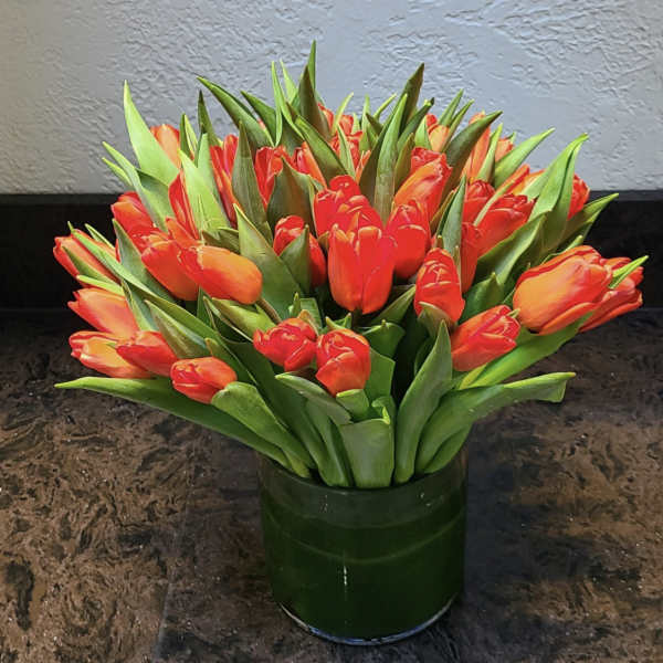Orange tulips arranged in a dark green vase