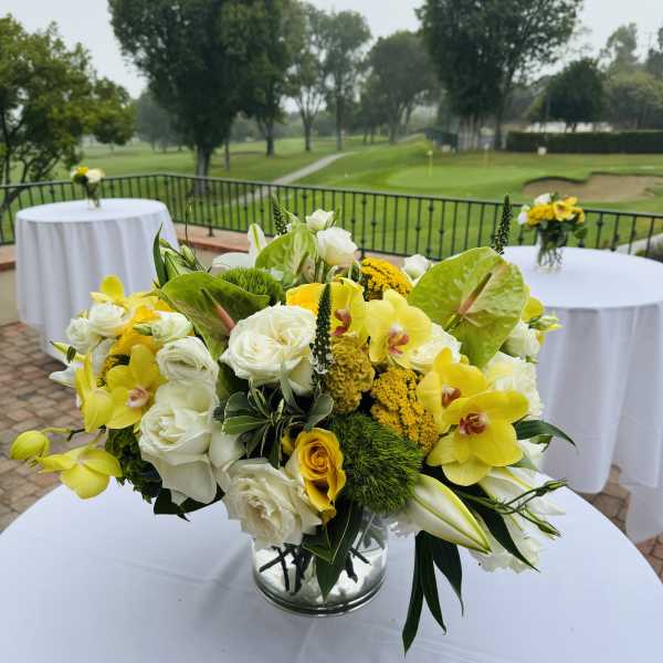 Yellow and white floral centerpiece in a glass vase