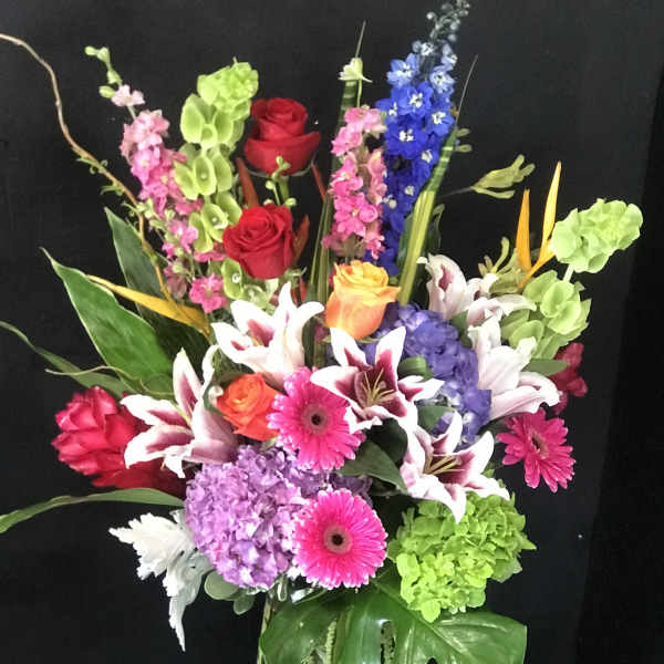 Colorful mixed bouquet in a glass vase with roses, lilies, and gerberas