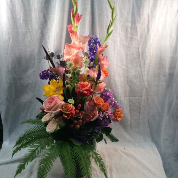 Tall mixed bouquet with pink, purple, orange, and yellow flowers in a vase