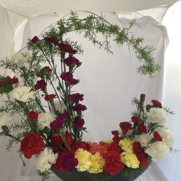 Carnation arrangement with red, white, yellow, and magenta blooms in a bowl vase