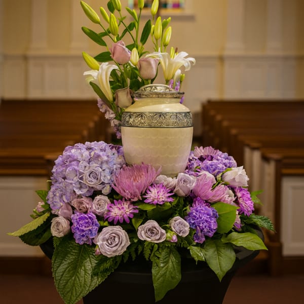Purple and white floral arrangement with lilies in a decorative urn
