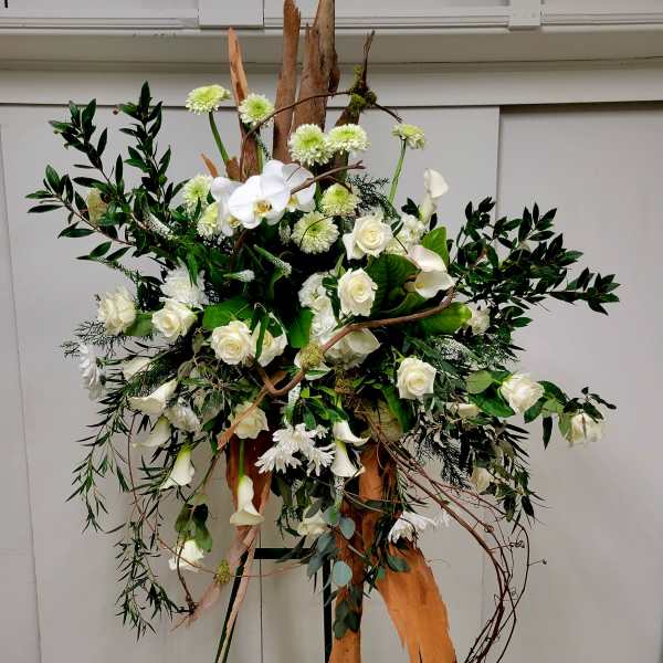 Tall floral arrangement with white roses and calla lilies on branches