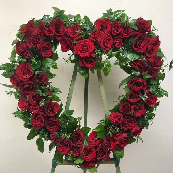 Heart-shaped wreath of red roses on a stand