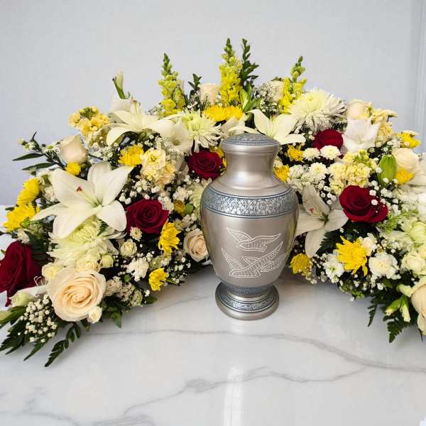 Symmetrical funeral floral arrangement with a silver urn in the center