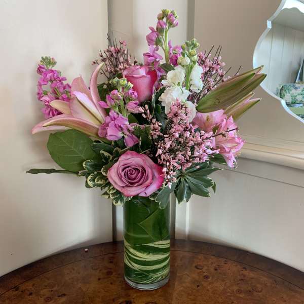 Pink and white flowers arranged in a tall glass vase